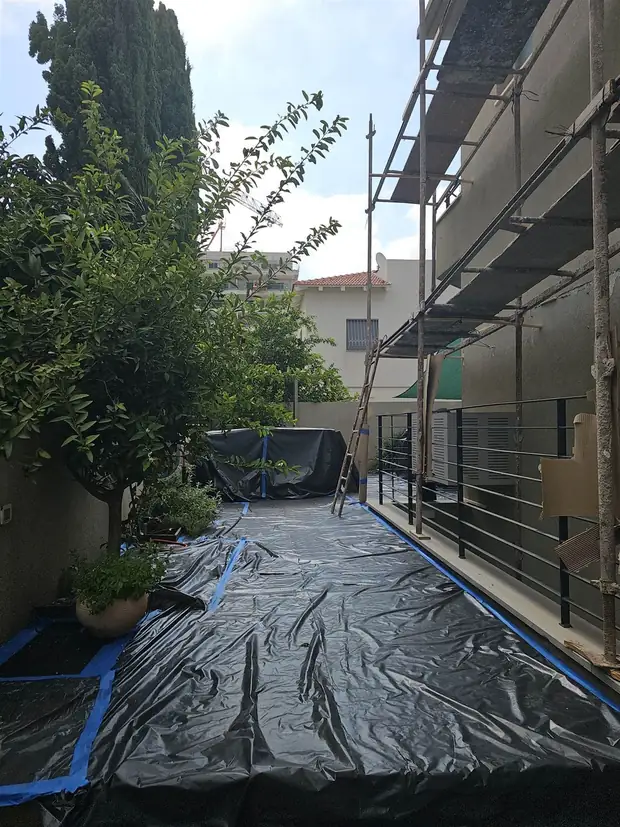 חצר מכוסה בניילון שחור ומודבקת בסרט כחול לפני תחילת עבודה